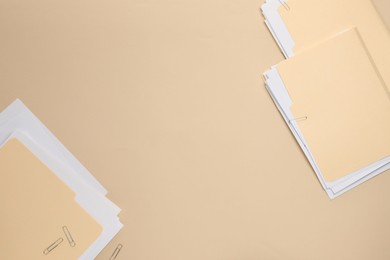 Photo of File folders with papers on beige background, flat lay. Space for text