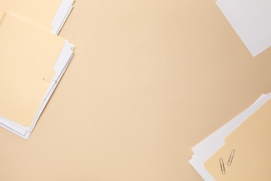 Photo of File folders with papers on beige background, flat lay. Space for text