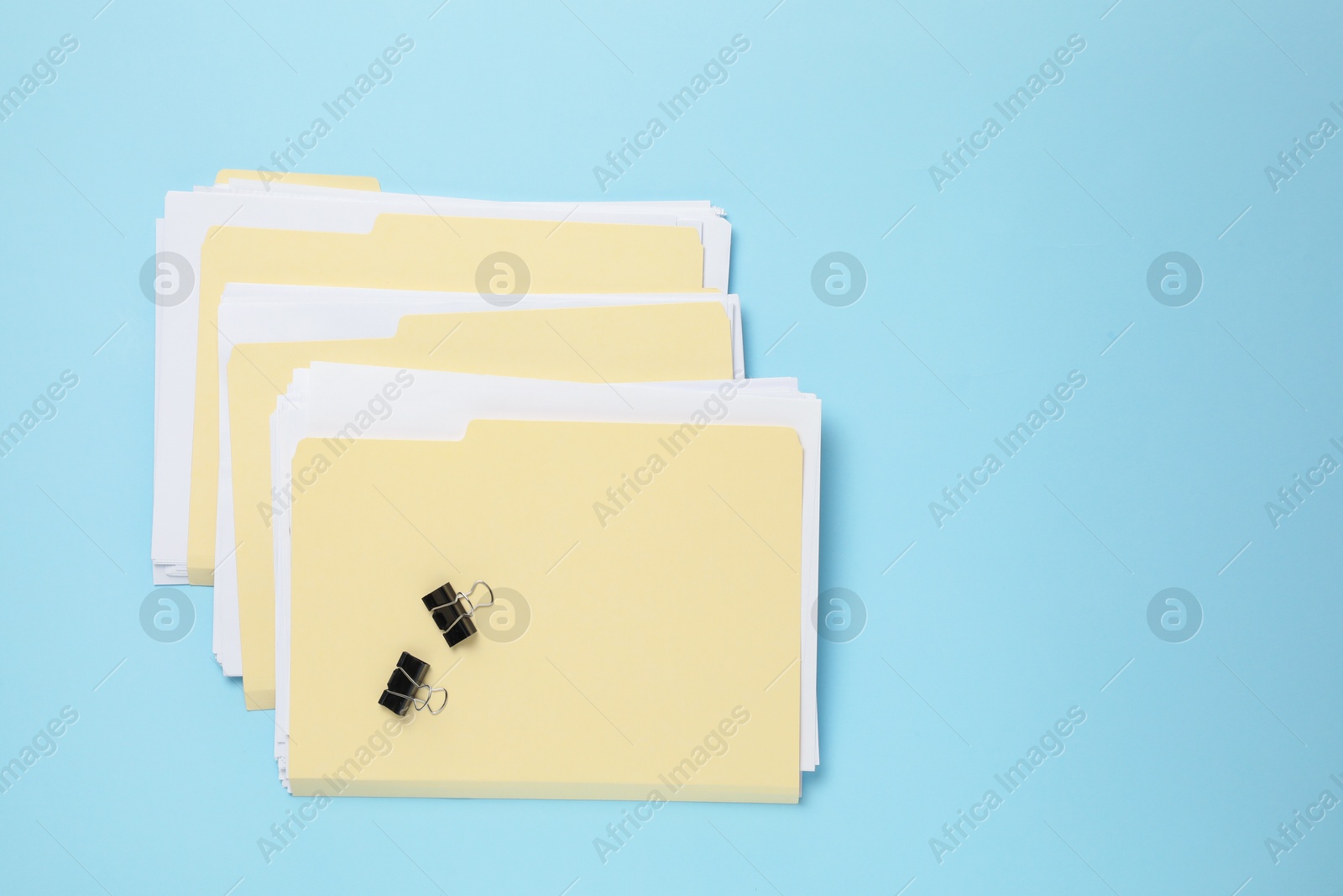 File folders with papers and binder clips on light blue background, flat lay. Space for text Photo of File folders with papers and binder clips on light blue background, flat lay. Space for text