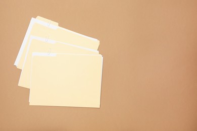 Photo of File folders with papers on light brown background, flat lay. Space for text
