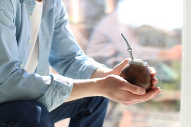 Photo of Man with traditional yerba mate tea at home, closeup