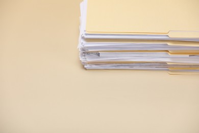 Photo of File folders with papers on pale yellow background, closeup. Space for text