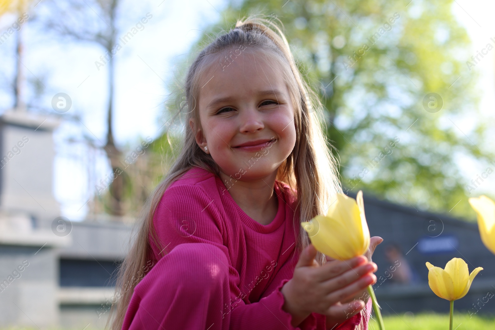 Cute little girl near beautiful yellow tulips outdoors Photo of Cute little girl near beautiful yellow tulips outdoors