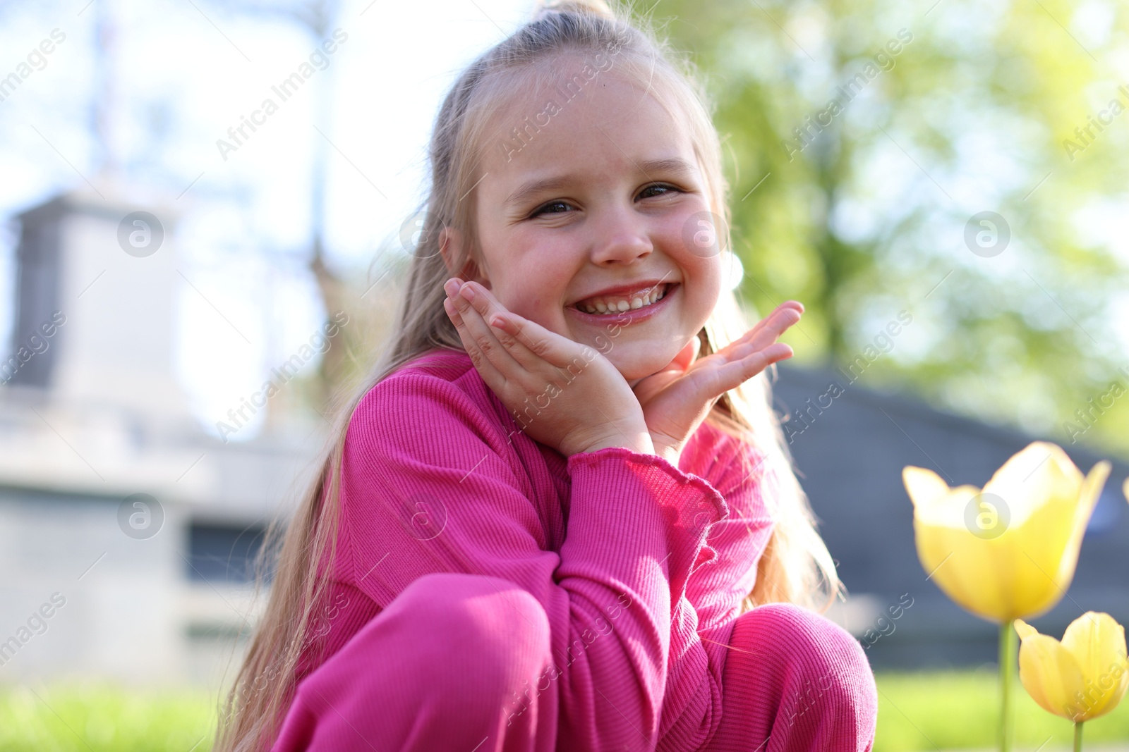 Cute little girl near beautiful yellow tulips outdoors Photo of Cute little girl near beautiful yellow tulips outdoors