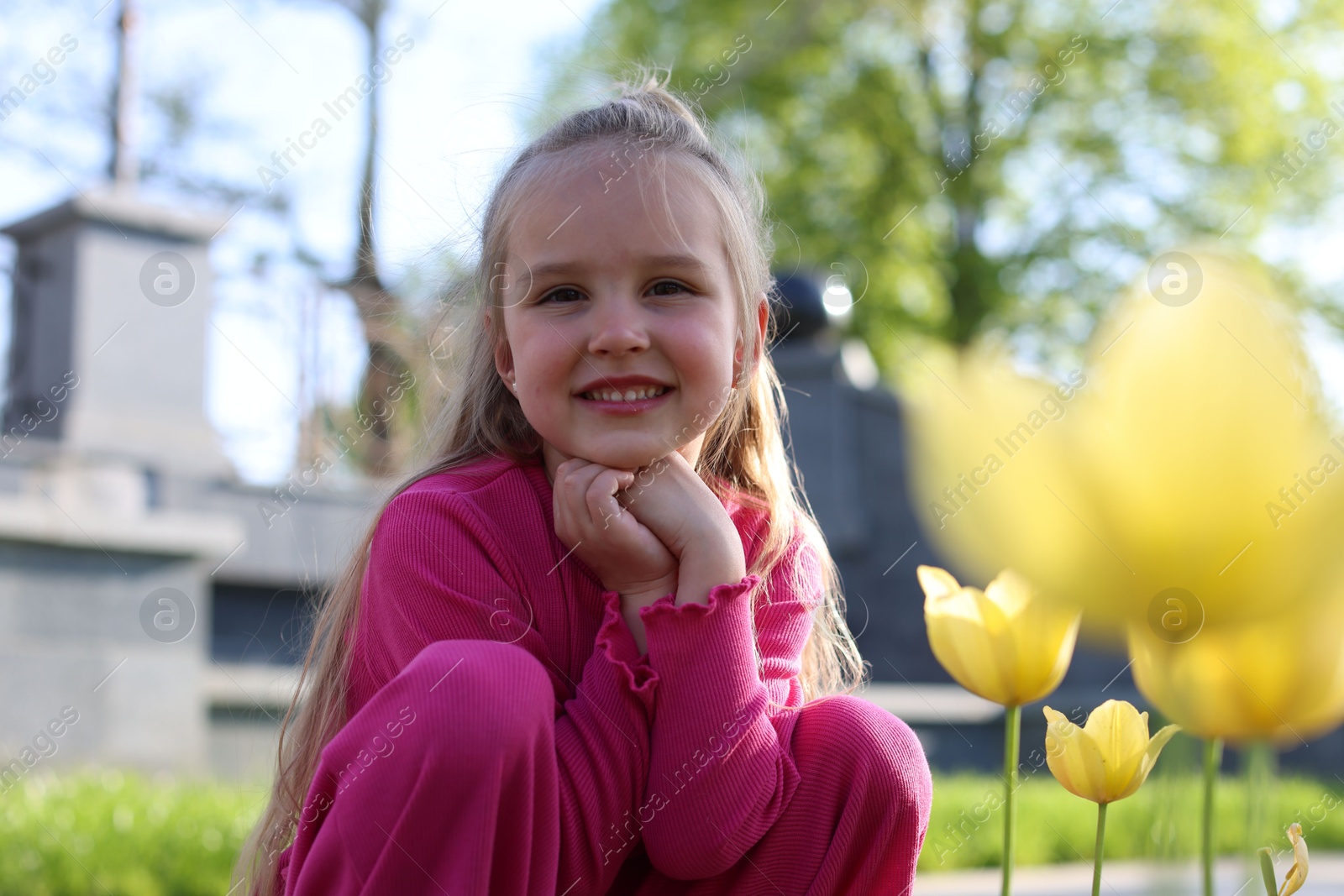 Cute little girl near beautiful yellow tulips outdoors Photo of Cute little girl near beautiful yellow tulips outdoors