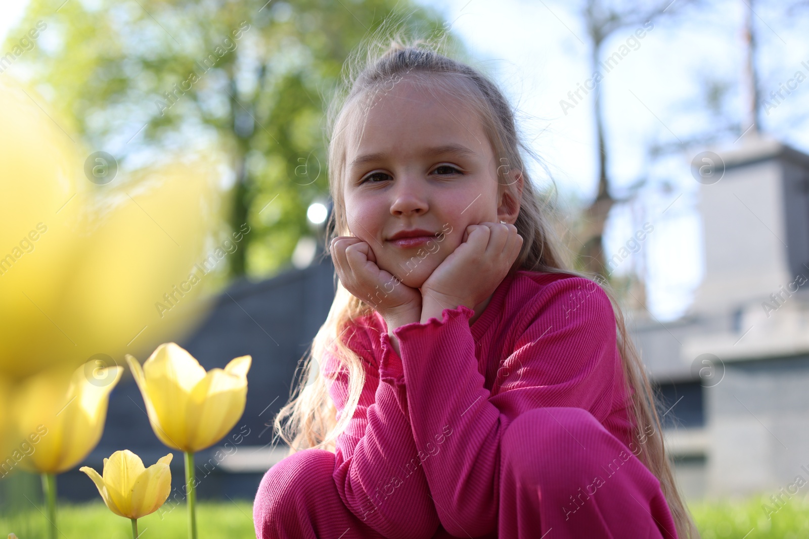 Cute little girl near beautiful yellow tulips outdoors Photo of Cute little girl near beautiful yellow tulips outdoors