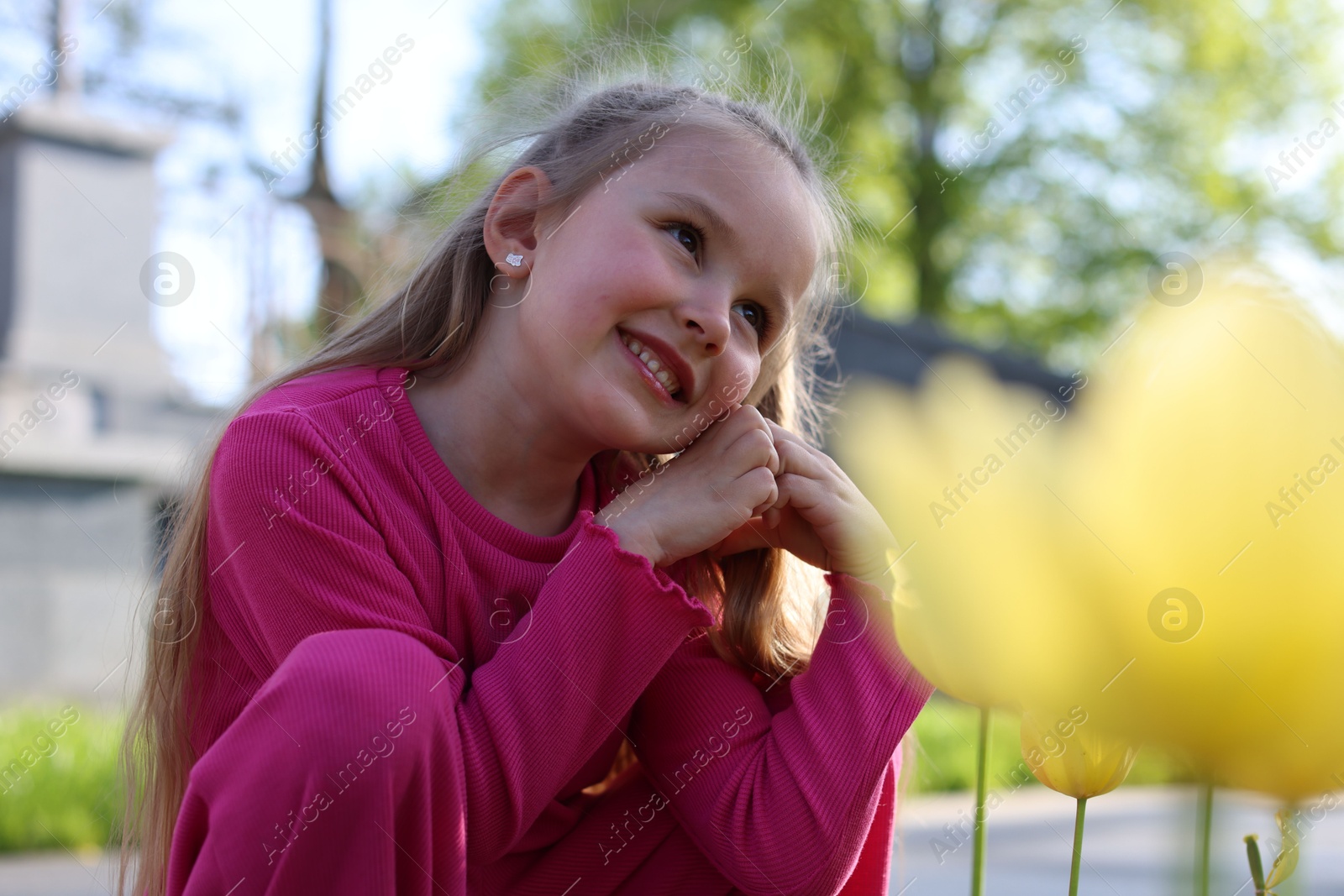 Cute little girl near beautiful yellow tulips outdoors Photo of Cute little girl near beautiful yellow tulips outdoors