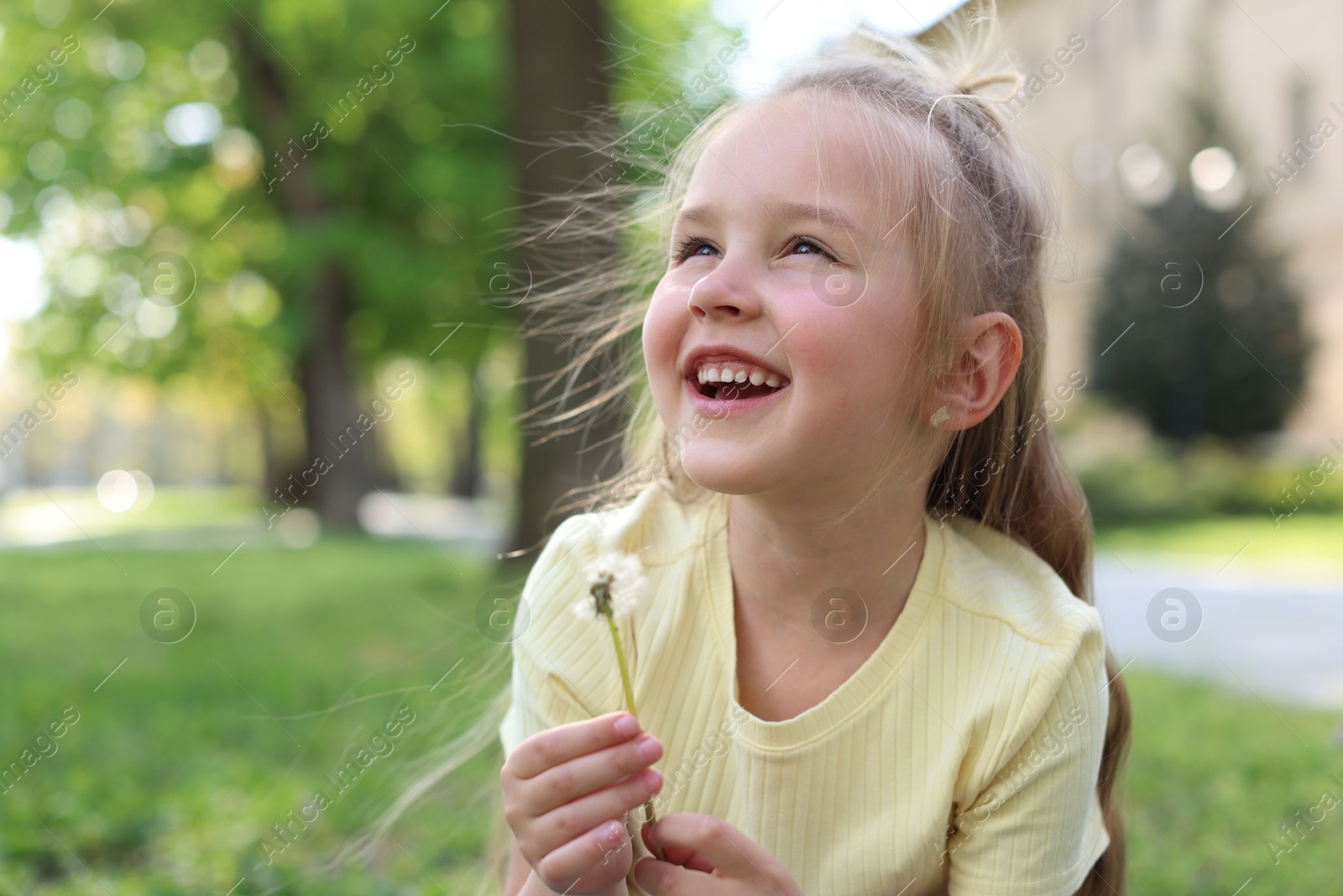 Photo of Cute little girl with beautiful dandelion outdoors