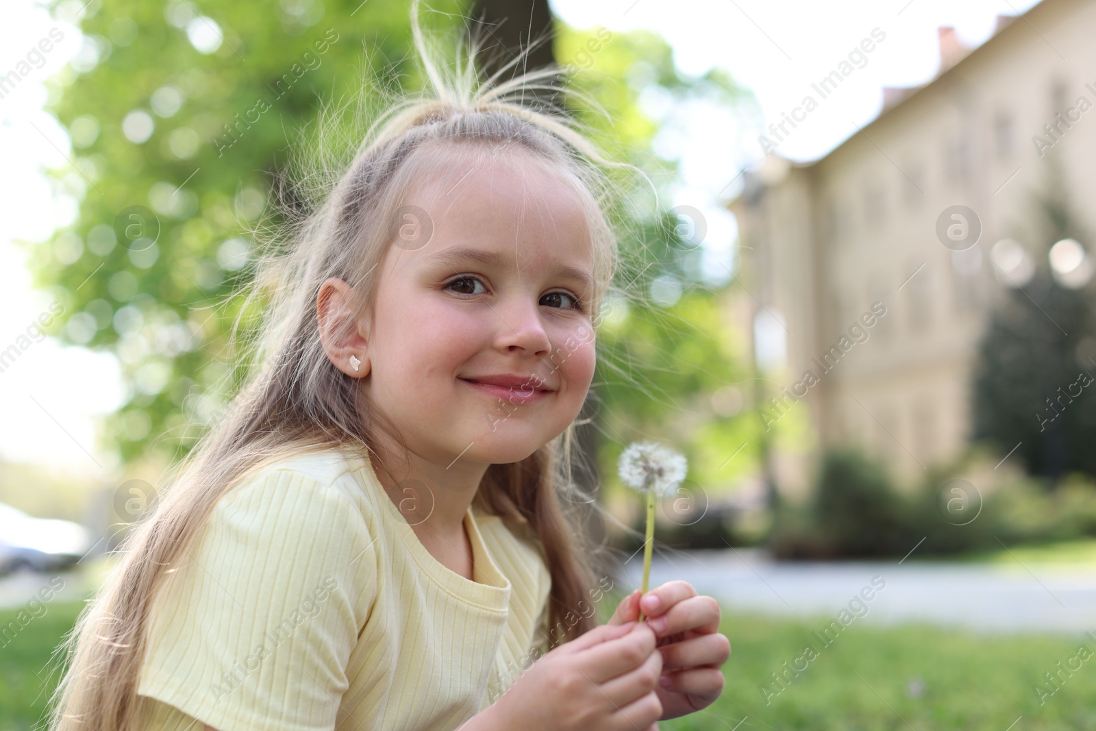 Photo of Cute little girl with beautiful dandelion outdoors, space for text