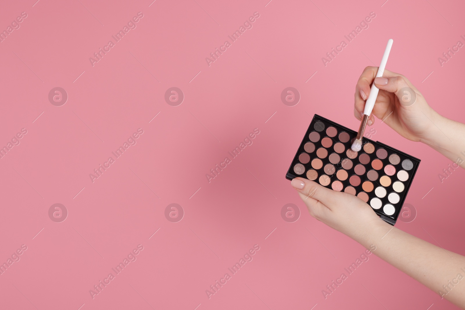 Woman with eyeshadow palette and brush on pink background, closeup. Space for text Photo of Woman with eyeshadow palette and brush on pink background, closeup. Space for text