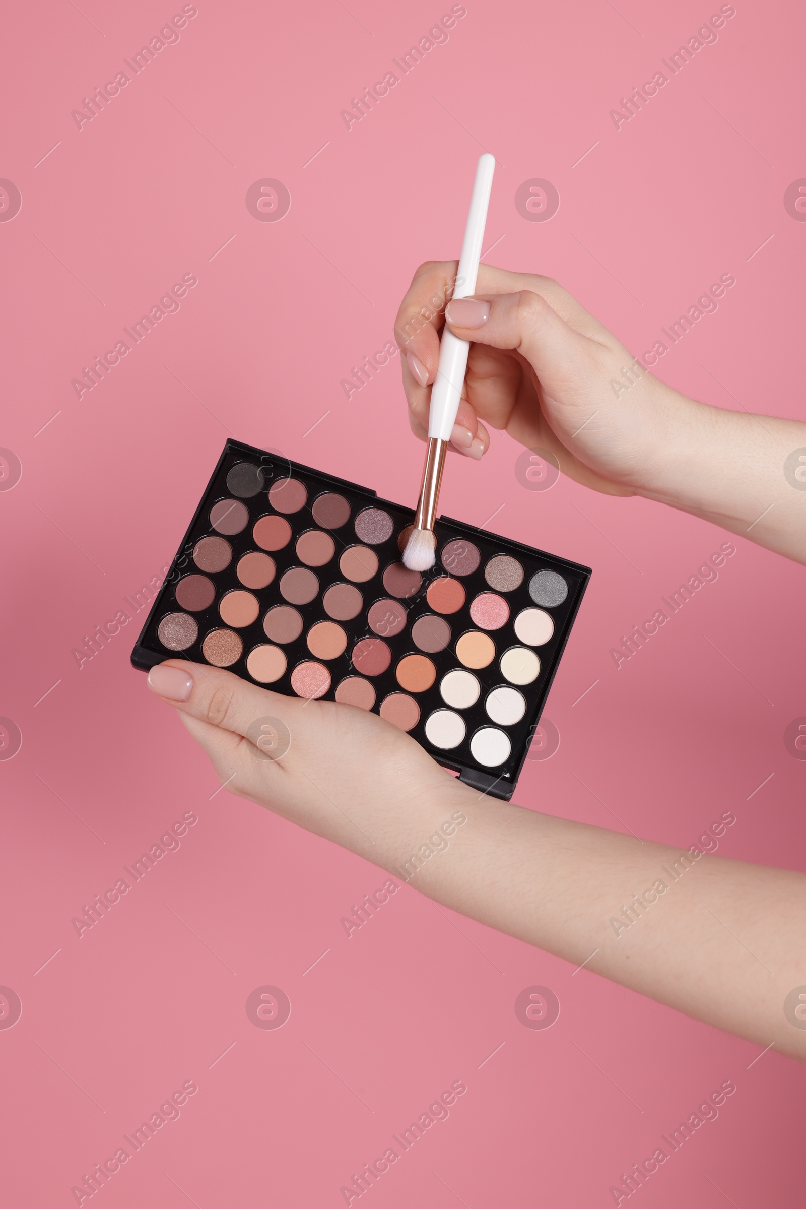 Woman with eyeshadow palette and brush on pink background, closeup Photo of Woman with eyeshadow palette and brush on pink background, closeup