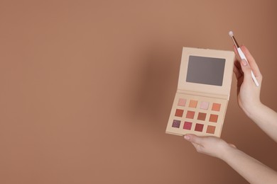 Photo of Woman with eyeshadow palette and brush on beige background, closeup. Space for text