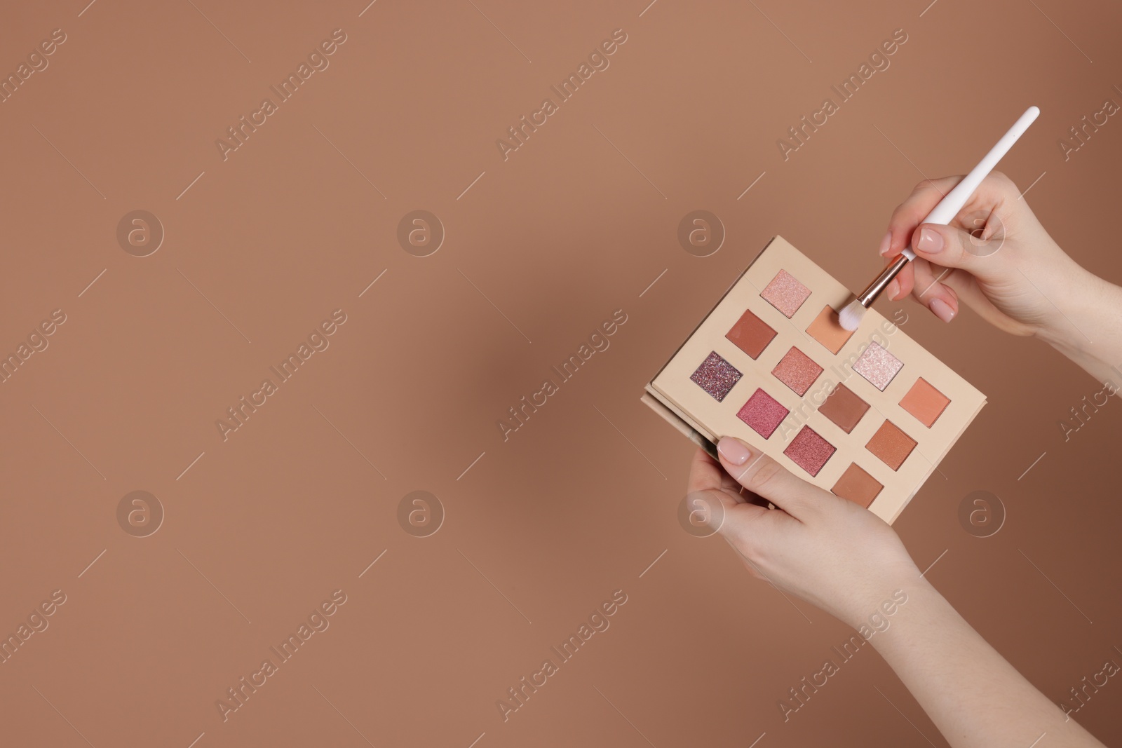 Woman with eyeshadow palette and brush on beige background, closeup. Space for text Photo of Woman with eyeshadow palette and brush on beige background, closeup. Space for text
