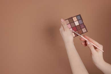 Photo of Woman with eyeshadow palette and brush on beige background, closeup. Space for text