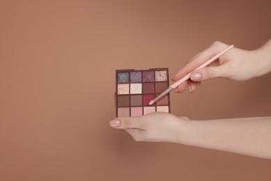Photo of Woman with eyeshadow palette and brush on beige background, closeup. Space for text