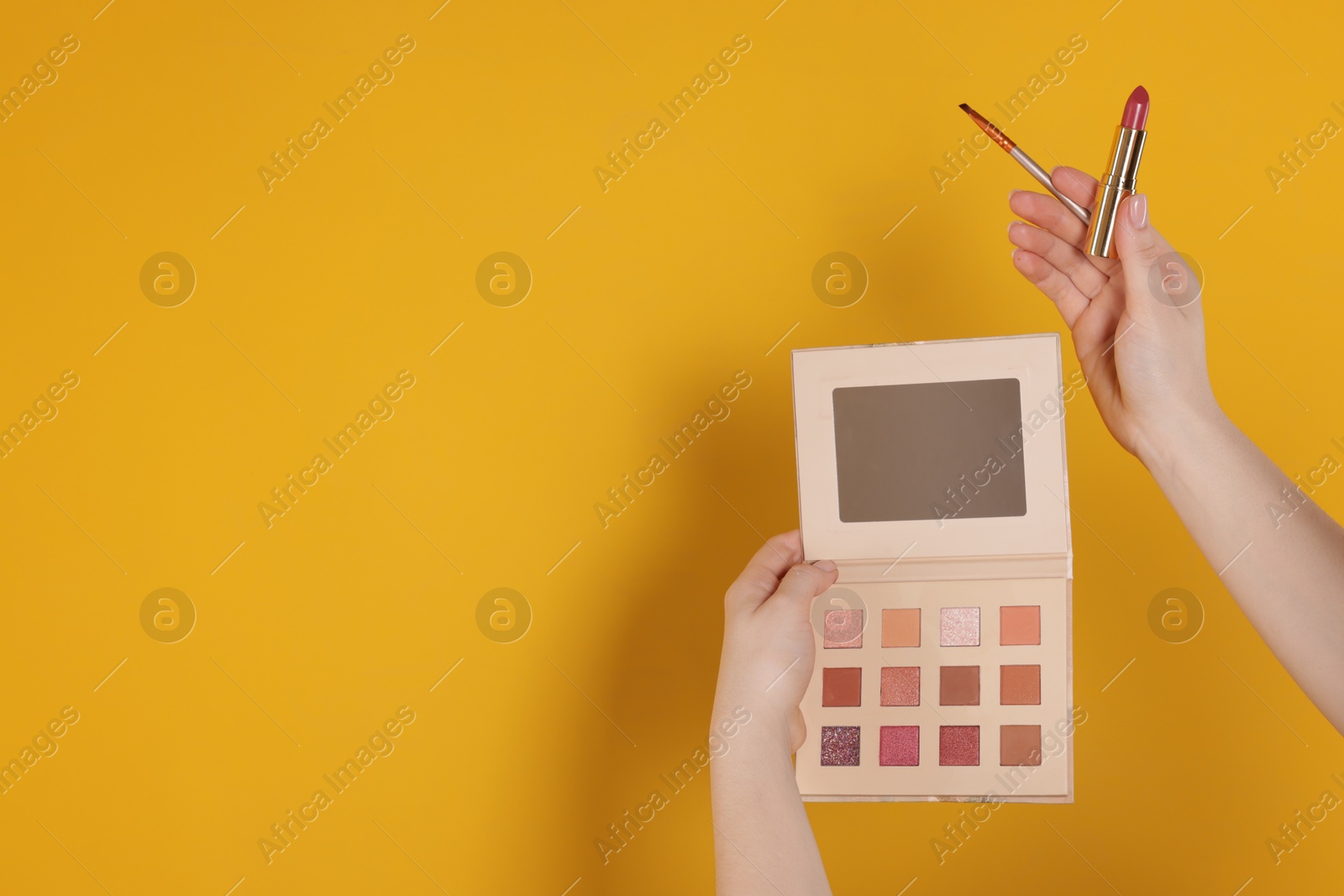 Woman with eyeshadow palette, lipstick and brush on yellow background, closeup. Space for text Photo of Woman with eyeshadow palette, lipstick and brush on yellow background, closeup. Space for text