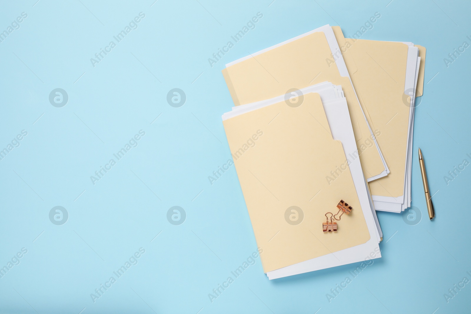 File folders with papers, pen and binder clips on light blue background, flat lay. Space for text Photo of File folders with papers, pen and binder clips on light blue background, flat lay. Space for text