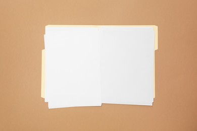 Photo of Paper file folder with blank sheets on light brown background, top view