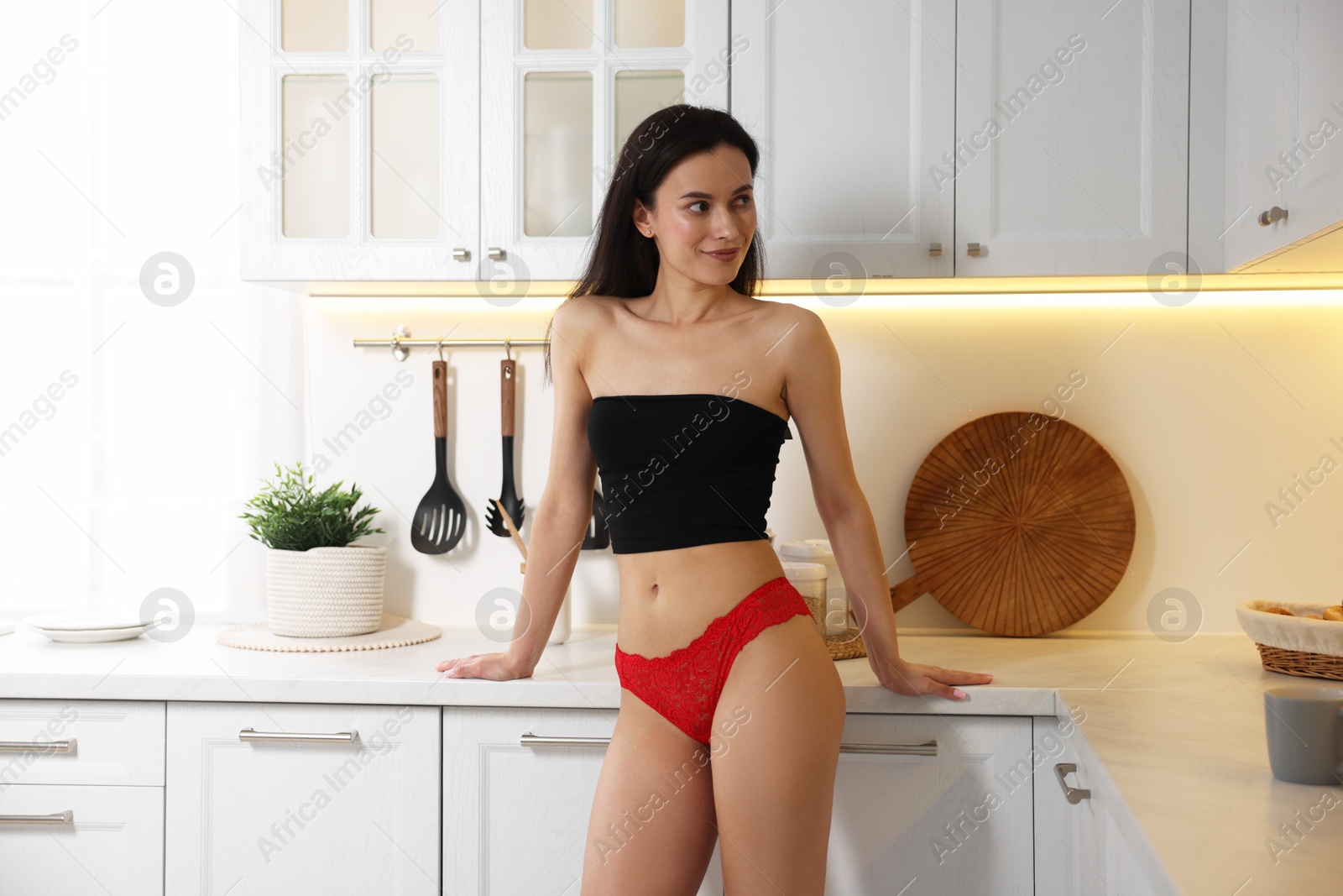 Photo of Woman wearing beautiful lace underwear in kitchen