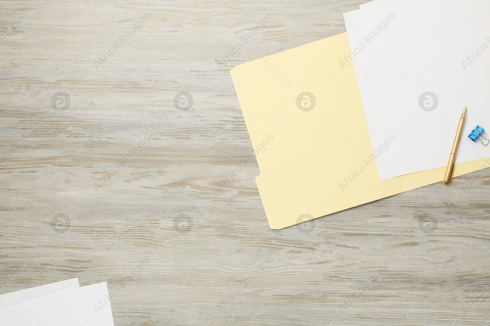 Paper file folder with blank sheets, pen and binder clip on wooden table, flat lay. Space for text Photo of Paper file folder with blank sheets, pen and binder clip on wooden table, flat lay. Space for text