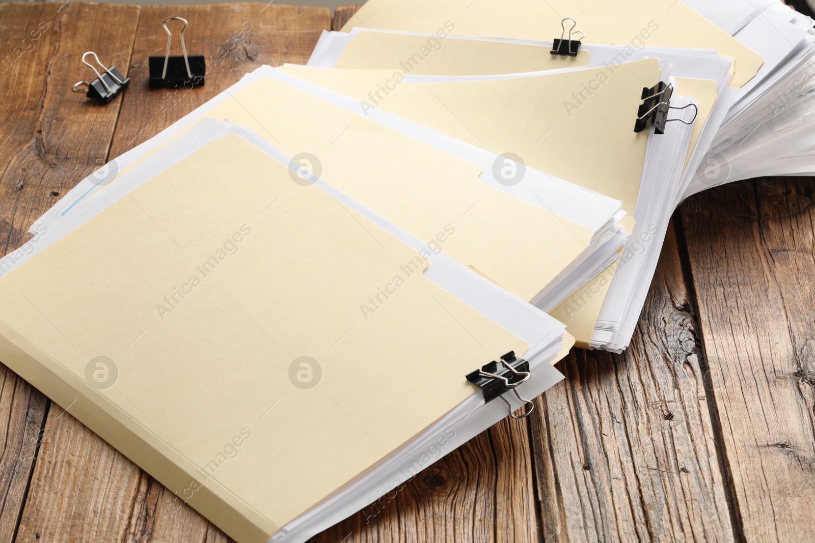 File folders with papers and binder clips on wooden table, closeup Photo of File folders with papers and binder clips on wooden table, closeup