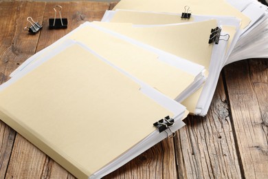 Photo of File folders with papers and binder clips on wooden table, closeup