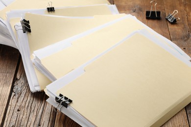 Photo of File folders with papers and binder clips on wooden table, closeup