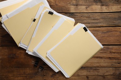Photo of File folders with papers and binder clips on wooden table, flat lay