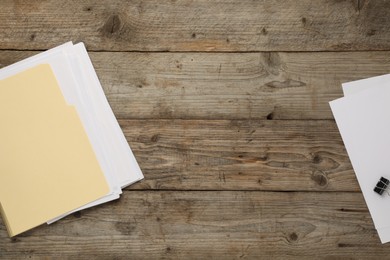 Photo of File folders with papers and binder clip on wooden table, flat lay. Space for text