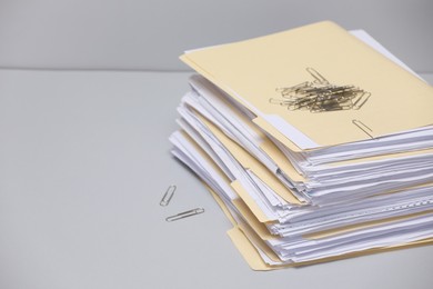 Photo of File folders with documents and paper clips on gray background, closeup. Space for text