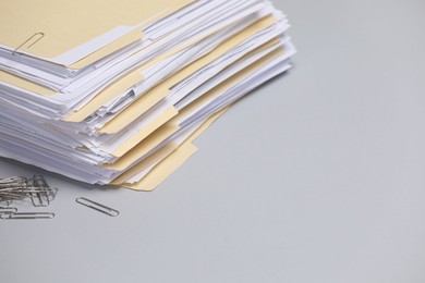 Photo of File folders with documents and paper clips on gray background, closeup. Space for text