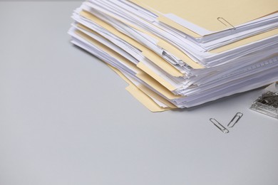 Photo of File folders with documents and paper clips on gray background, closeup. Space for text
