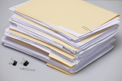 Photo of File folders with papers and binder clips on gray background, closeup