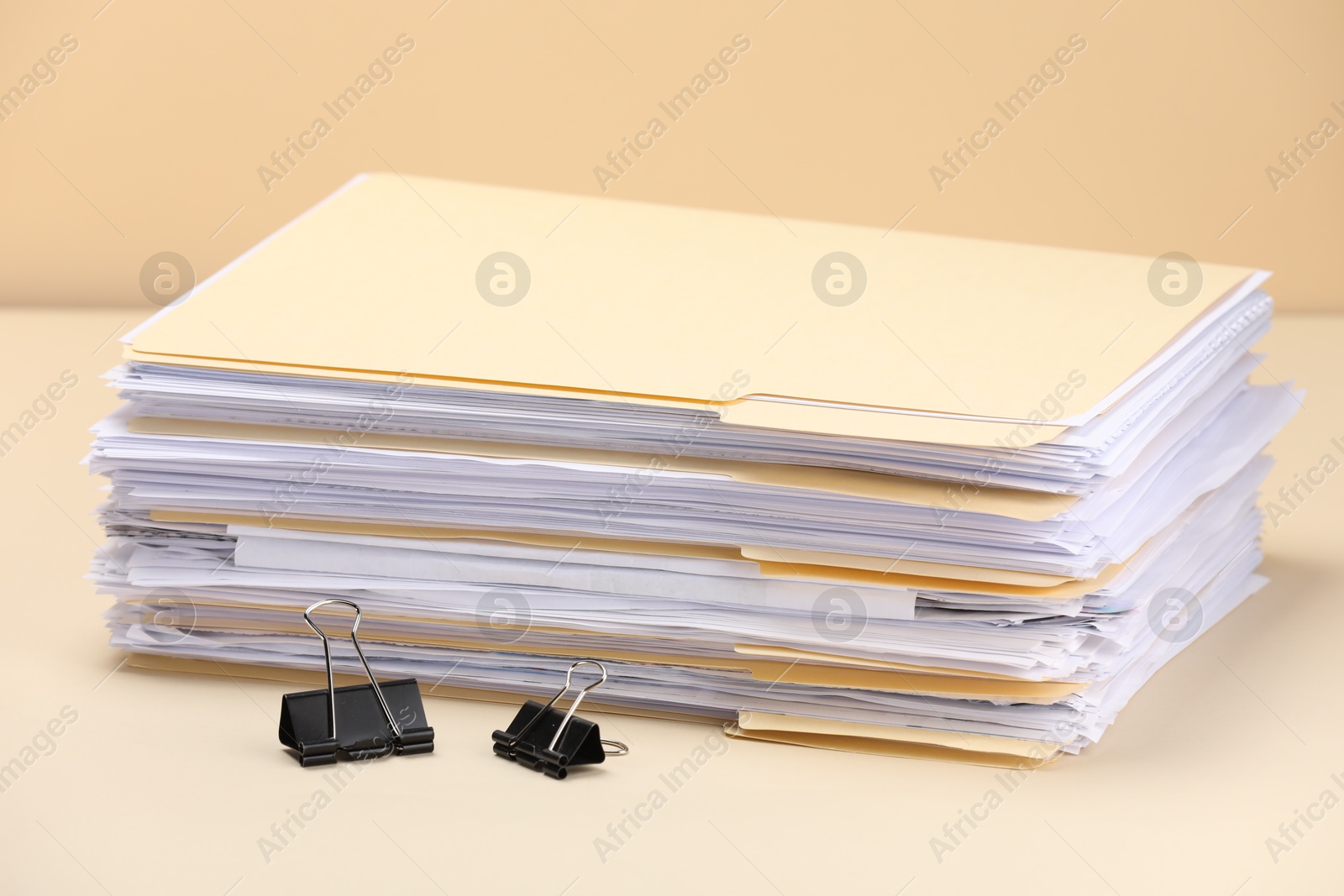 File folders with papers and binder clips on pale yellow background, closeup Photo of File folders with papers and binder clips on pale yellow background, closeup