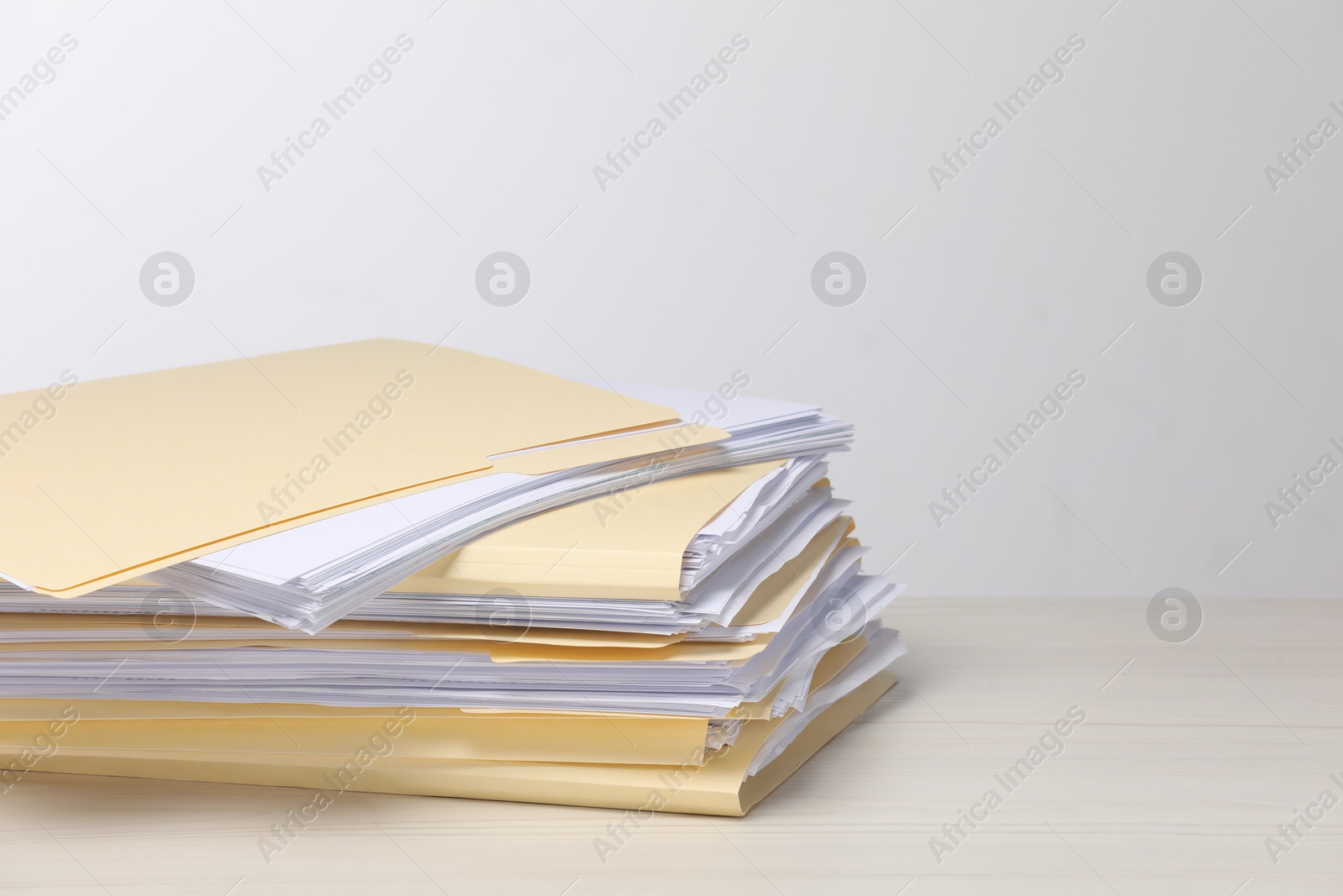 File folders with papers on wooden table against light background, space for text Photo of File folders with papers on wooden table against light background, space for text