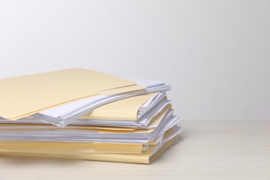Photo of File folders with papers on wooden table against light background, space for text