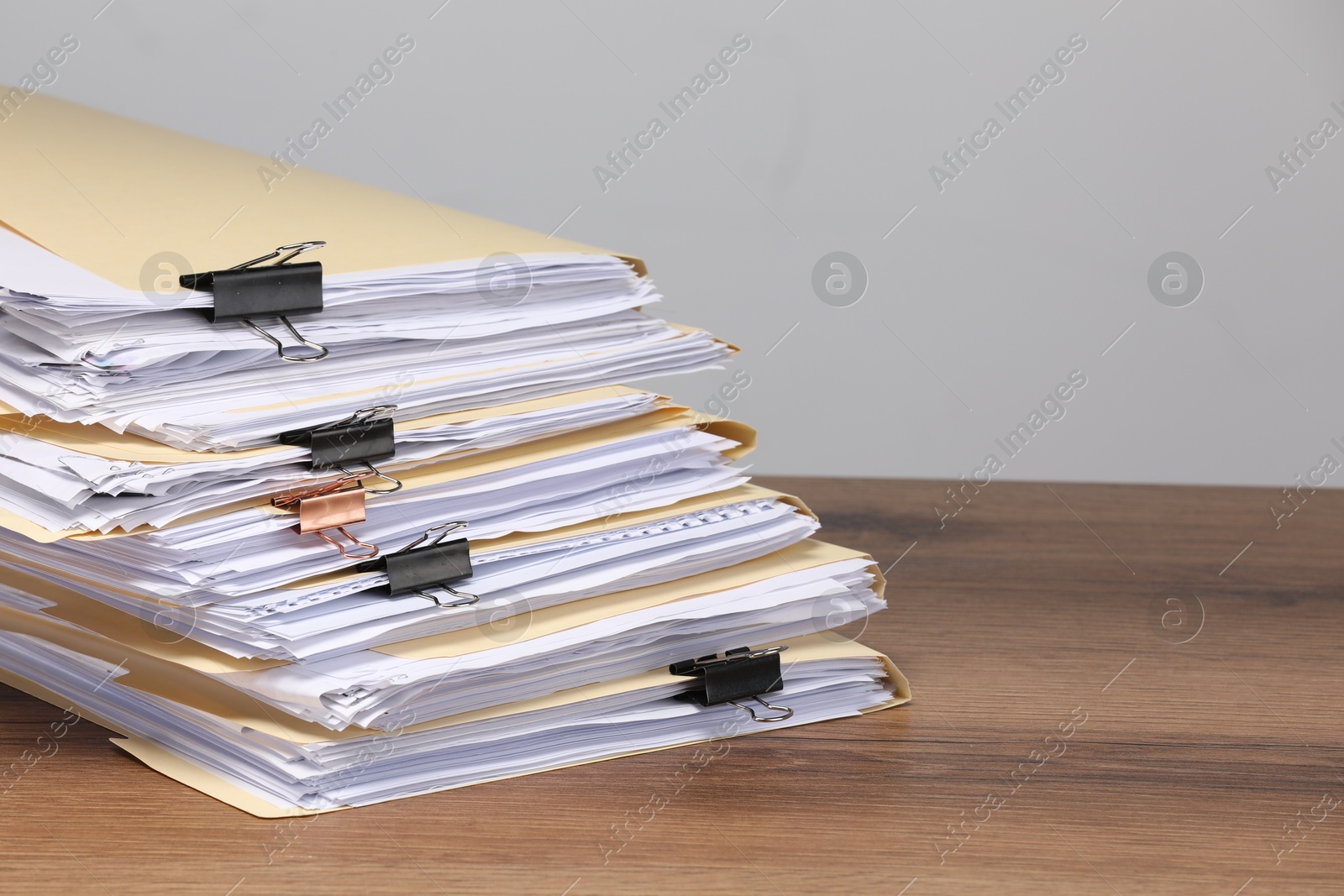 File folders with papers and binder clips on wooden table against gray background, closeup. Space for text Photo of File folders with papers and binder clips on wooden table against gray background, closeup. Space for text