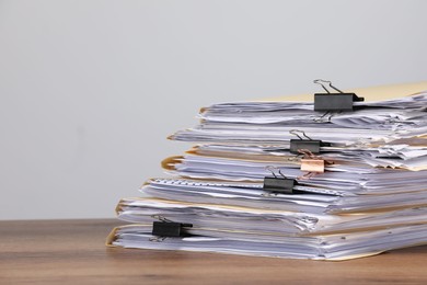 Photo of File folders with papers and binder clips on wooden table against gray background, closeup