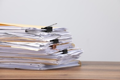 Photo of File folders with papers and binder clips on wooden table against gray background, closeup. Space for text