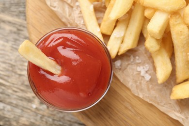 Photo of Tasty french fries served with ketchup on wooden table, top view