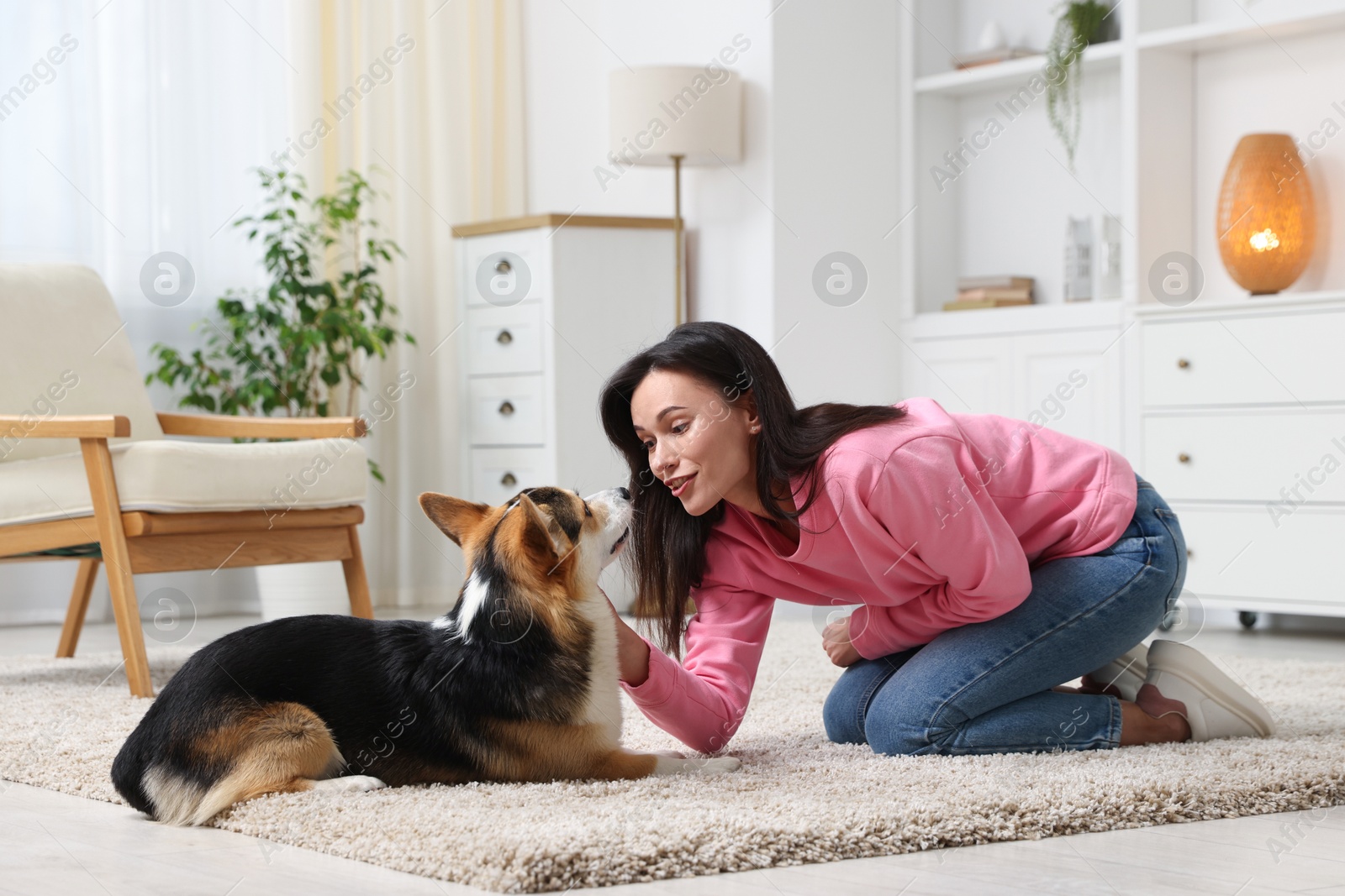 Photo of Happy woman training her dog on floor at home