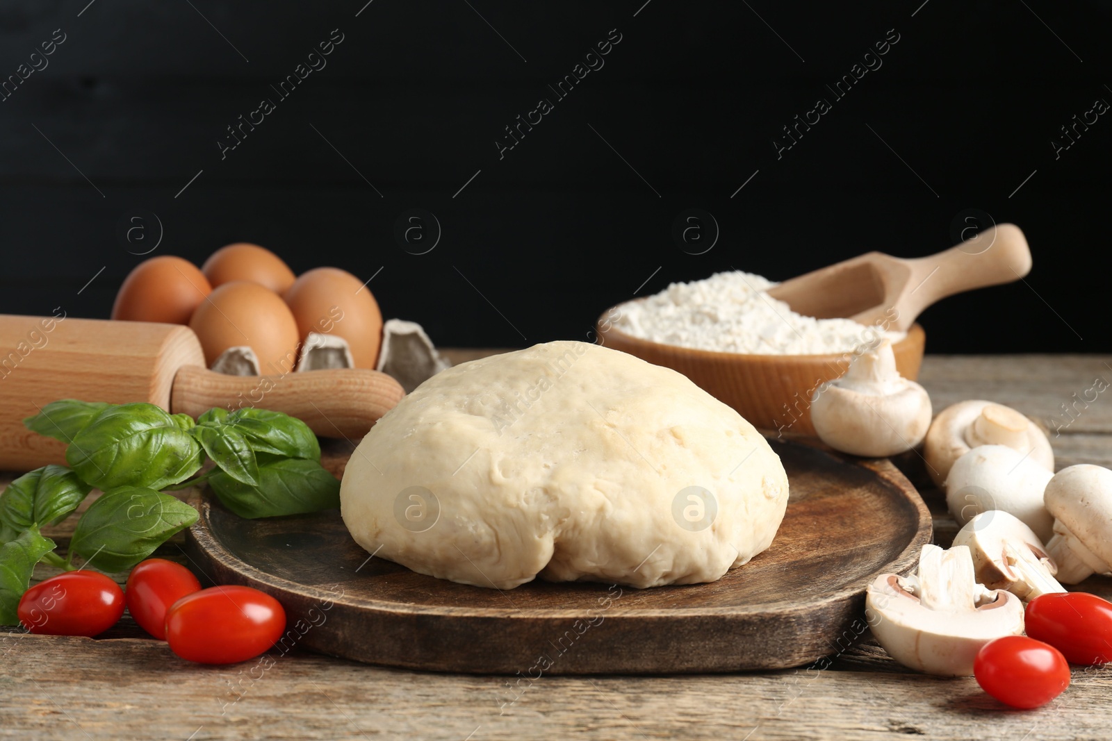 Making pizza. Different ingredients on wooden table against black background, closeup Photo of Making pizza. Different ingredients on wooden table against black background, closeup
