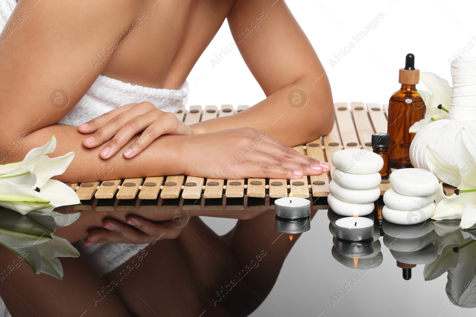 Woman relaxing on bamboo mat against white background, closeup. Different spa products and lily flowers on mirror surface Photo of Woman relaxing on bamboo mat against white background, closeup. Different spa products and lily flowers on mirror surface