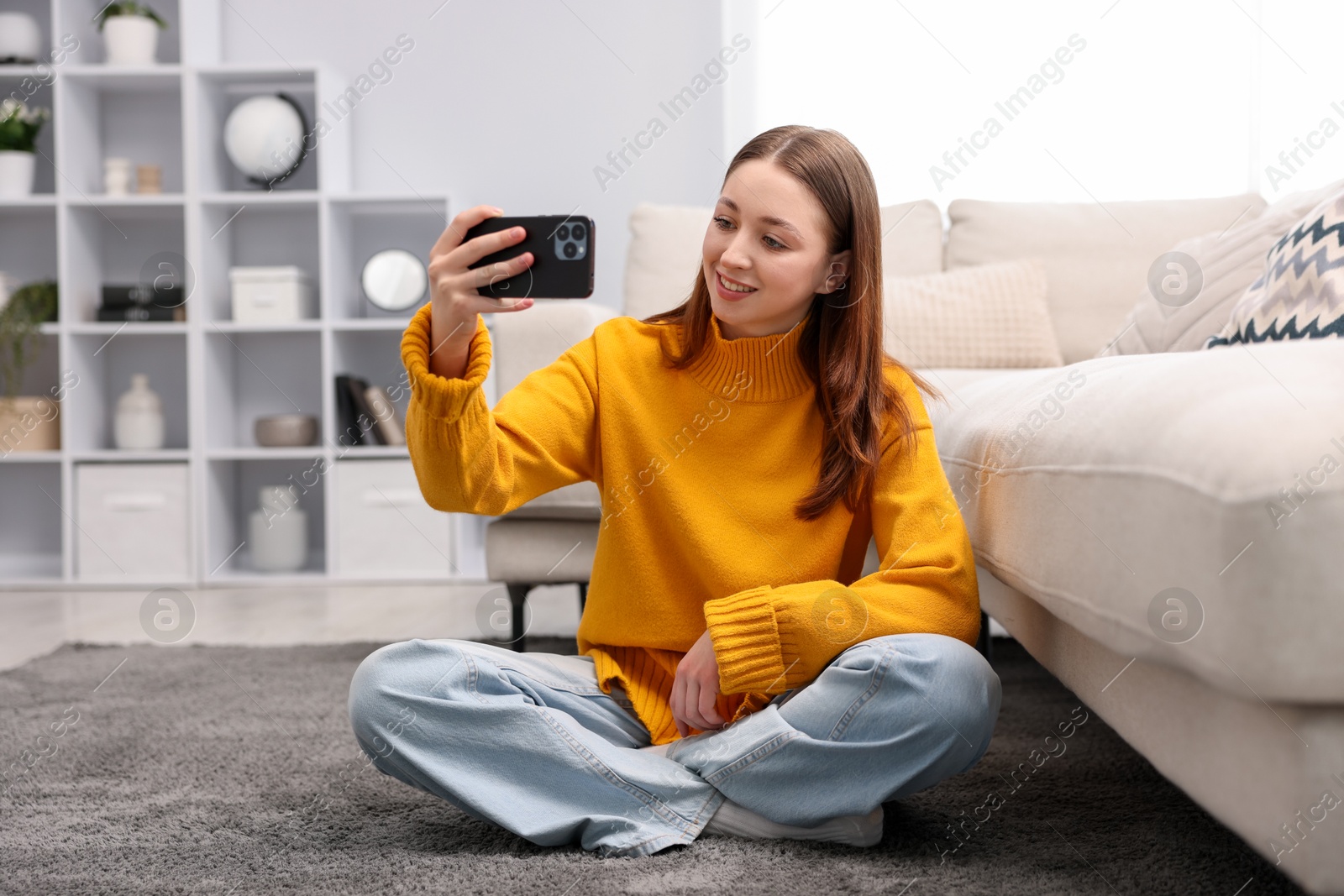 Teenage girl taking selfie on floor at home Photo of Teenage girl taking selfie on floor at home