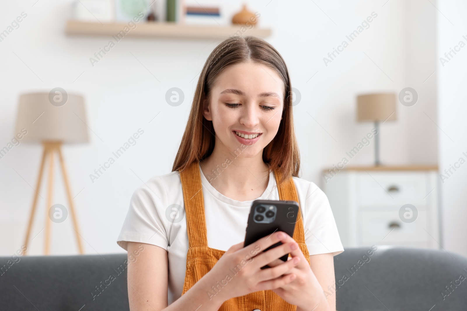 Happy teenage girl using smartphone at home Photo of Happy teenage girl using smartphone at home