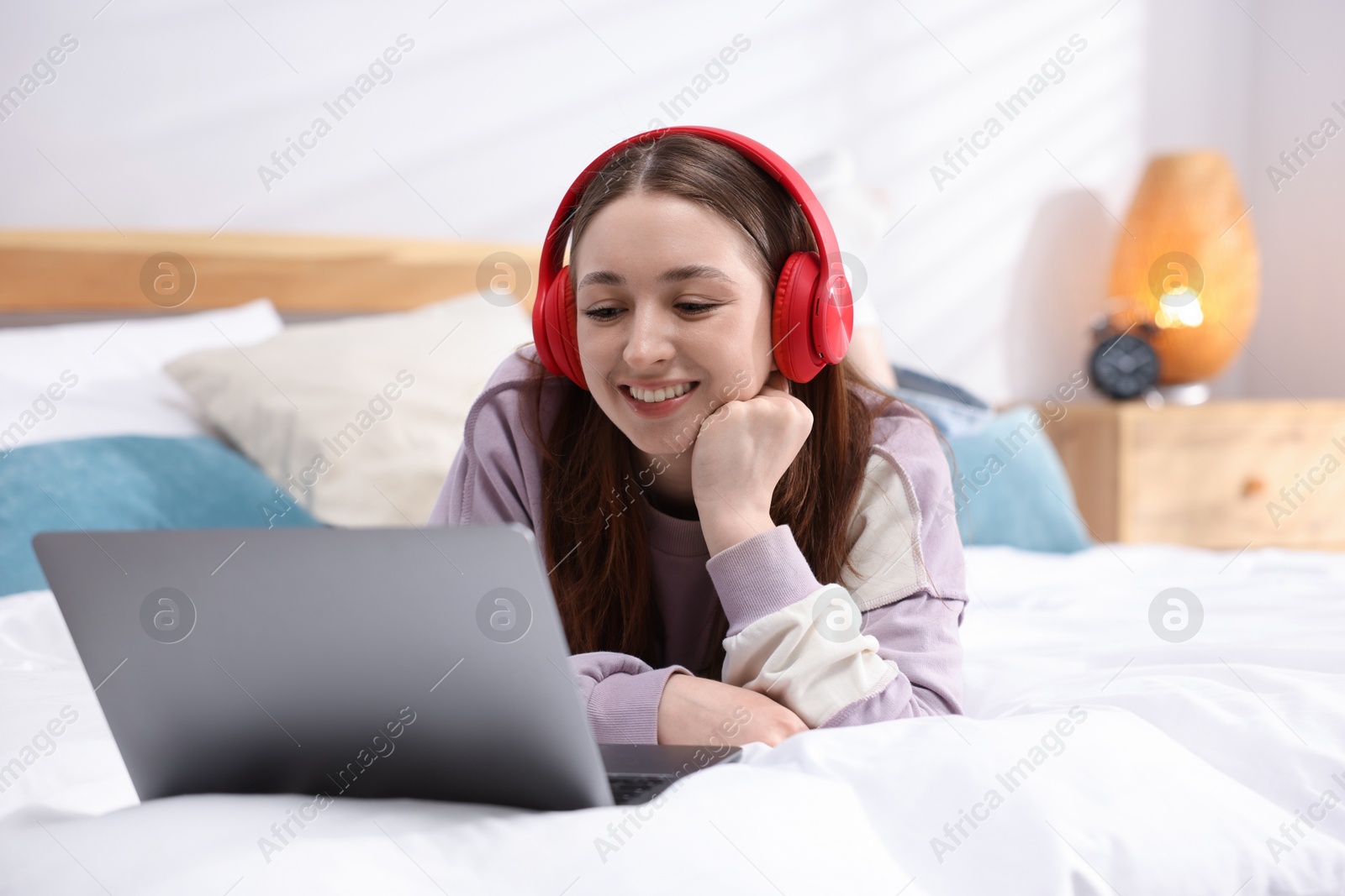 Photo of Teenage girl in headphones watching something on laptop at home