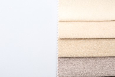 Photo of Samples of different fabrics on white background, top view. Space for text