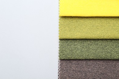 Photo of Samples of different fabrics on white background, top view. Space for text