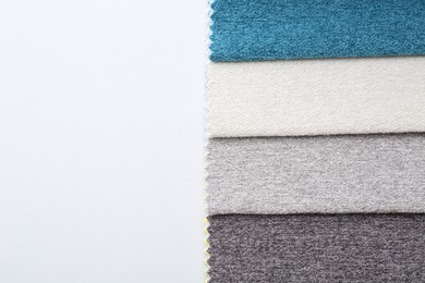 Photo of Samples of different fabrics on white background, top view. Space for text