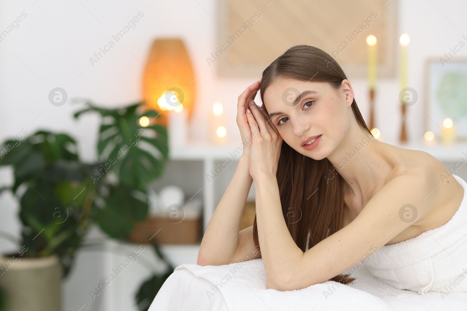 Photo of Beautiful woman relaxing on massage couch in spa salon. Space for text